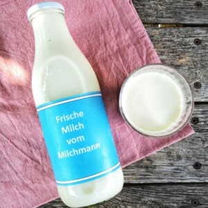 Milch in einer Glasflasche liegend von oben fotografiert und ein Glas Milch daneben